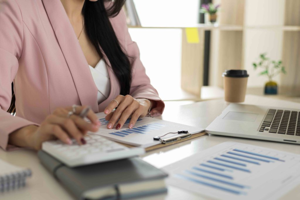 Businesswoman using calculator and laptop for do math finance on desk, tax, accounting, statistics and analytical research concept.